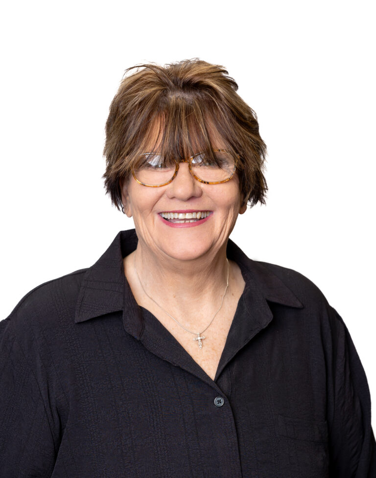 A woman with short brown hair and glasses smiles while wearing a black shirt with a collar, against a plain white background. She could be your new go-to for Baton Rouge real estate, thanks to her expertise at the local property management company.