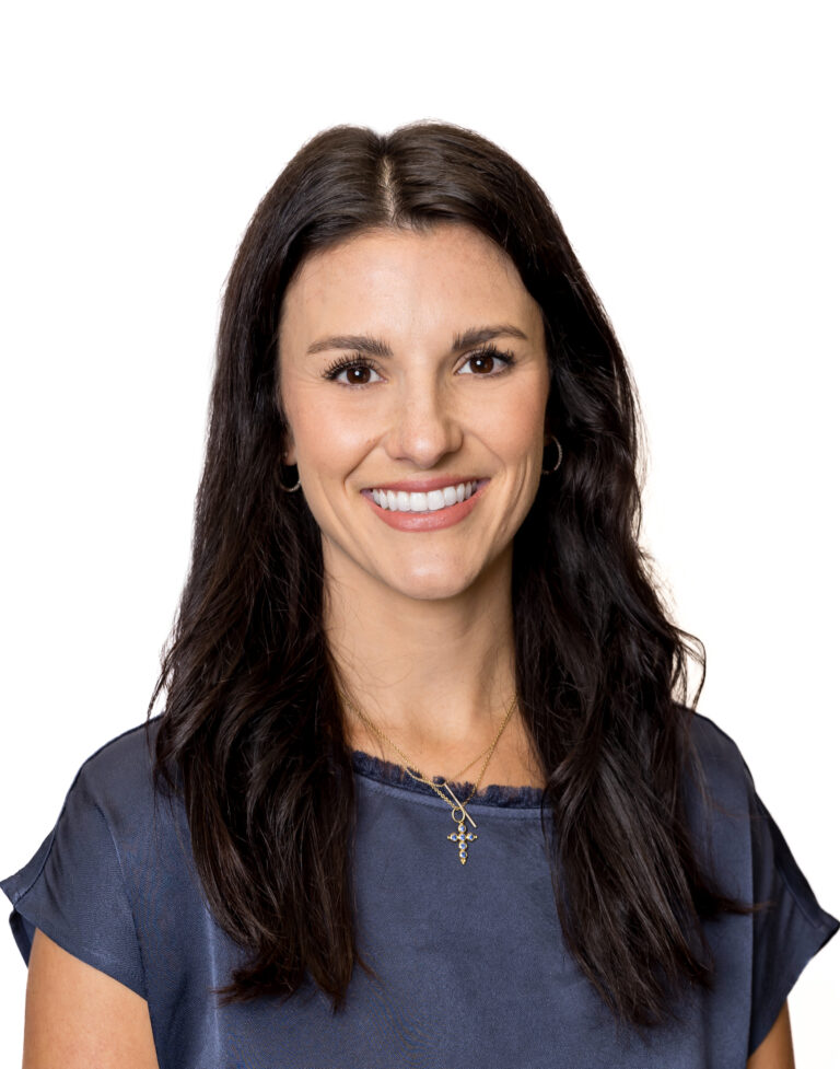 A woman with long dark hair and a blue top smiles at the camera against a plain white background, representing a Baton Rouge real estate property management company.